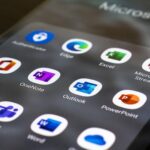 Smartphone met Microsoft-apps zoals Outlook, Teams, Word en Excel op het startscherm.